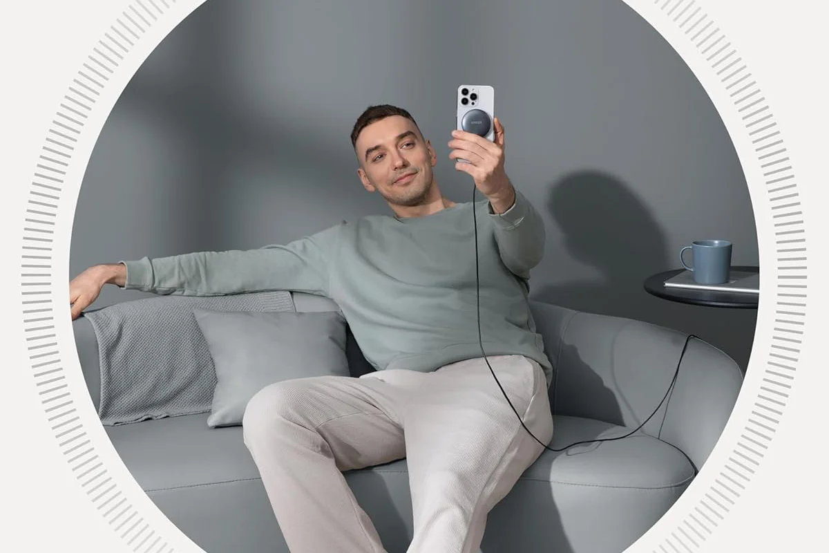 A person holds up their phone while it’s magnetically attached to Anker’s MagGo 15W Qi2 wireless charging pad.